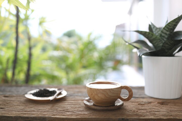 tea in wooden tea cup and dried tea leaves on wooden table