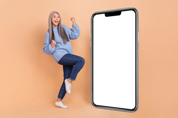 Full size photo of cheerful overjoyed woman celebrate big bargains promote product isolated on beige color background