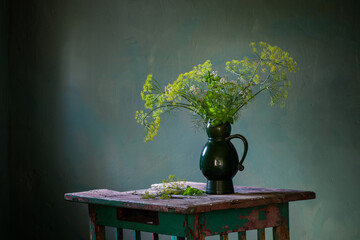 vintage bouquet with dill in ceramic jug on old wooden table on dark background