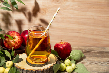 Glass of apple juice and apples in the garden under sunlight. The concept of harvesting the autumn harvest of apples copy space for text