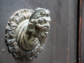 Decoration with a man's face sticking out his tongue on an old door in Venice, Italy