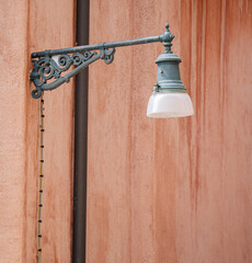 A street light on the red facade of a house in the middle of Venice