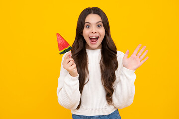 Funny child with lollipop over yellow isolated background. Sweet childhood life. Teen girl with yummy caramel lollipop, candy shop. Excited teenager girl.