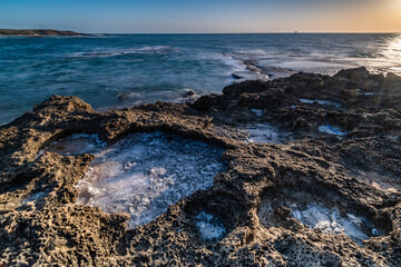 Sunset over salt circles in the rocky beach Nachsholim Israel