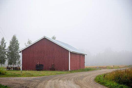 A big red agricultural building, a quiet crossing of two village roads with sand, fog in the background.