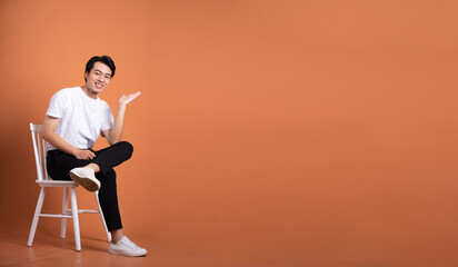 Fototapeta na wymiar man sitting on chair isolated on orange background
