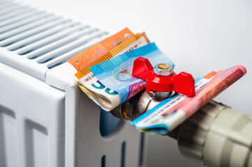 euro banknotes in a central heating radiator, the concept of expensive heating costs, closeup