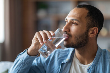 Fototapeta na wymiar Portrait Of Handsome Young Black Man Drinking Water From Glass