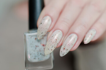 beautiful female hands with long nails light white manicure and a bottle of nail polish