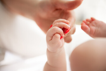 Hand in hand. Mom is holding her baby by the hand.