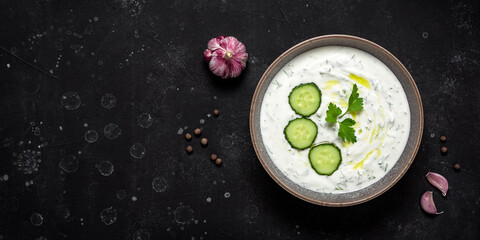 Greek tzatziki sauce on black stone background. View from above. Banner