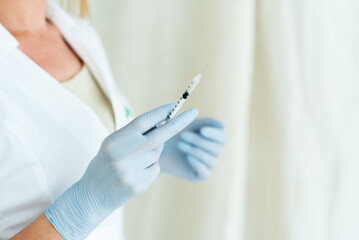 Cosmetologist in sterile gloves holds syringe for injection with collagen hyaluronic filler for face or lips rejuvenation