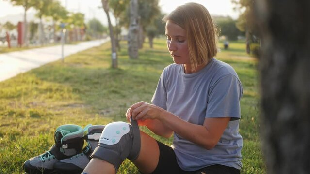 Woman putting on knee pads before training. Active outdoor sport. Close-up legs.