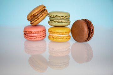 Pile of macarons of different colors on a blue background, with reflection. Concept of temptation, caprice, sweet.