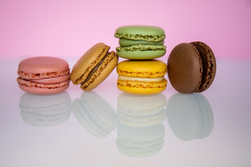 Pile of macarons, of different colors, on a pink background, with reflection. Concept of temptation, sugar, caprice