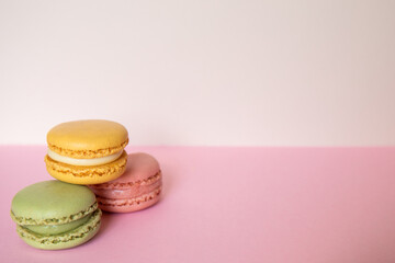 Pile of three macaroons in green, pink and blue color, on a pink background. Concept of sweet temptation, caprice. Copy space.