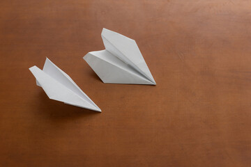 White paper plane on brown background, travel and holiday concept.