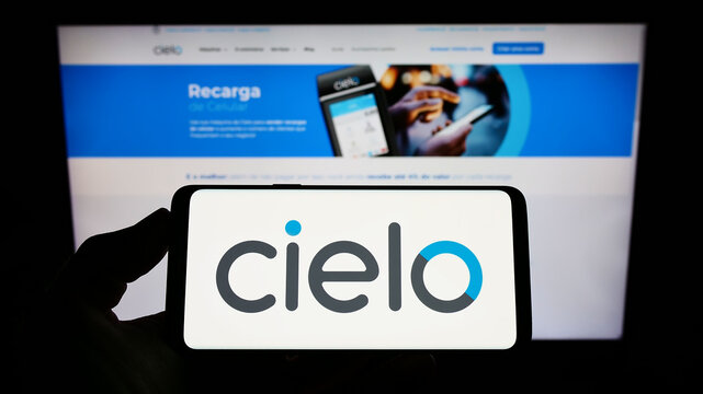 Stuttgart, Germany - 08-28-2022: Person holding smartphone with logo of Brazilian payments company Cielo S.A. on screen in front of website. Focus on phone display.