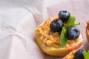 Blueberries on a baked apple in an oven with syrup, cinnamon and mint on parchment paper. Dietary eating. Autumn dish. Traditions of Ukrainian and German cuisine.