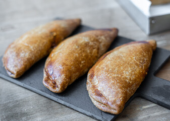 Close-up, three Spanish empanadillas on a black slate plate.