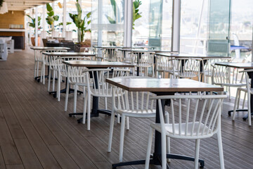 Empty restaurant with white chairs and wooden tables