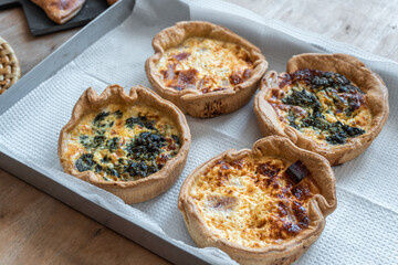 Four baked quiches on an aluminum tray
