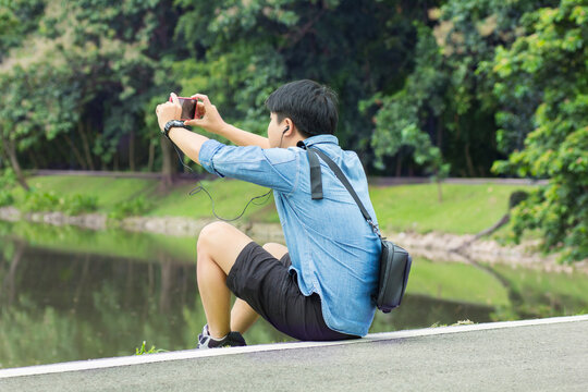 Asian man sitting chill out taking photo by using his mobile phone