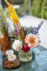 Fototapeta na wymiar Garden table decorated with different cut flowers in vases