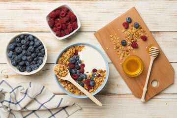 Bowl with granola, yogurt and fresh berries on wooden background, top view