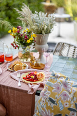 Breakfast on beautifully decorated table with flowers in garden
