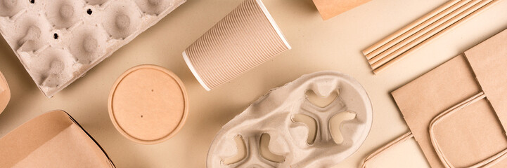 Banner with paper utensils over light brown background. Street food sustainable paper packaging. Eco- friendly food containers, cups and paper bags. Monochrome flat lay composition