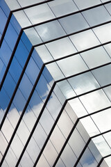 Part of a modern office building with the sky reflected in its mirrored glass panes. 