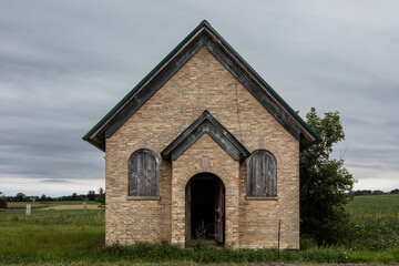 Fototapeta na wymiar Small brick church abandoned on side of rural rode on overcast day