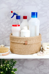 Hand knitted jute basket with a lid with detergents and towels in the bathroom on a white wooden rack