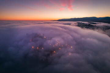 Fototapeta na wymiar Fotografía aérea del castillo de Peñíscola sumido en la niebla al anochecer con colores en el cielo.