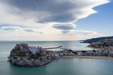 Fototapeta na wymiar Fotografía aérea de un atardecer en Peñíscola con nubes deformadas por el viento.