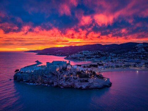 Fotograf&iacute;a a&eacute;rea del castillo de Pe&ntilde;&iacute;scola durante un atardecer con el cielo rojo.