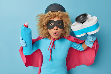 Scared woman pretends being superhero ready for cleaning house does domestic chores holds bottle of...