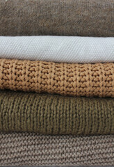 cozy autumn texture of knitted sweaters close-up in brown and beige colors vertically
