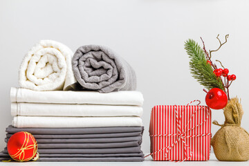 Stack of bed linen, bed sheet and folded rolls of towels on a table with Christmas decor