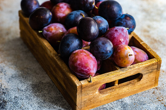 Organic ripe plums in wooden box
