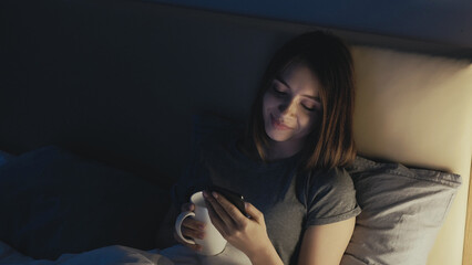 Online connection. Sleepless woman. Pretty lady in bed scrolling social media in smartphone...