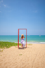 Tropical travel vacation. Traveler woman in red door on beach to turquoise sea