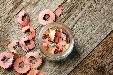 Pencil sharpening shavings in a glass on wooden background