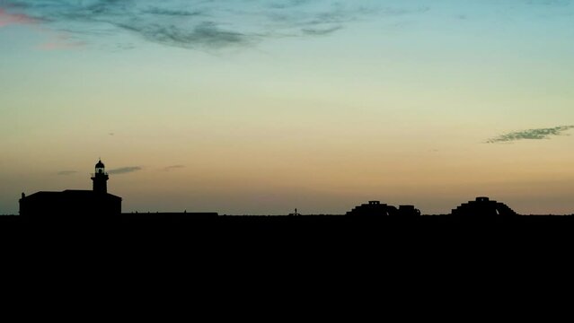 Timelapse of a sunset over the silhouette of Punta Nati lighthouse