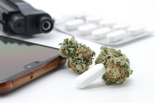 marijuana buds, pills and black gun isolated on white background (drug trafficking concept)