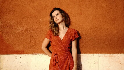 young woman thoughtful leaning against a street wall