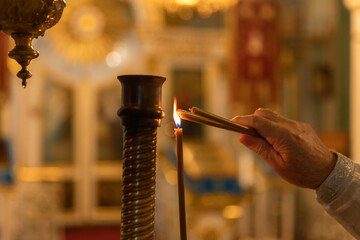 Orthodox Church. Christianity. Hand of priest lighting burning candles in traditional Orthodox...