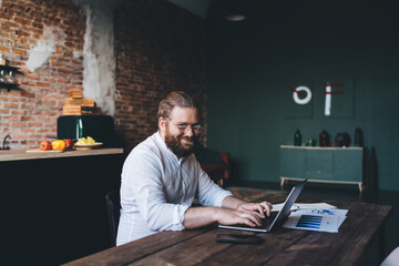 Obraz na płótnie Canvas Smiling businessman browsing laptop at home