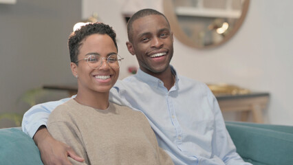 Portrait of Couple Smiling at Camera While Sitting on Sofa, Side Pose